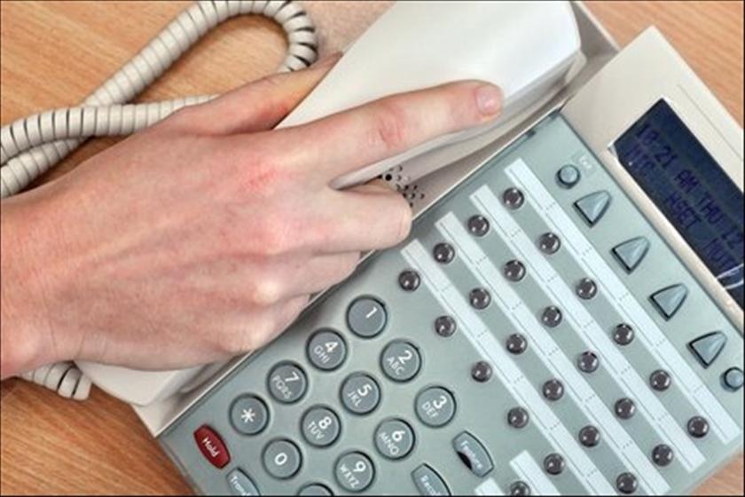 A person hangs up a landline telephone
