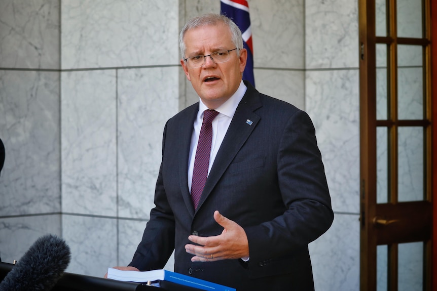 Scott Morrison stojący przed wejściem do parlamentu w sądzie premiera, za podium.