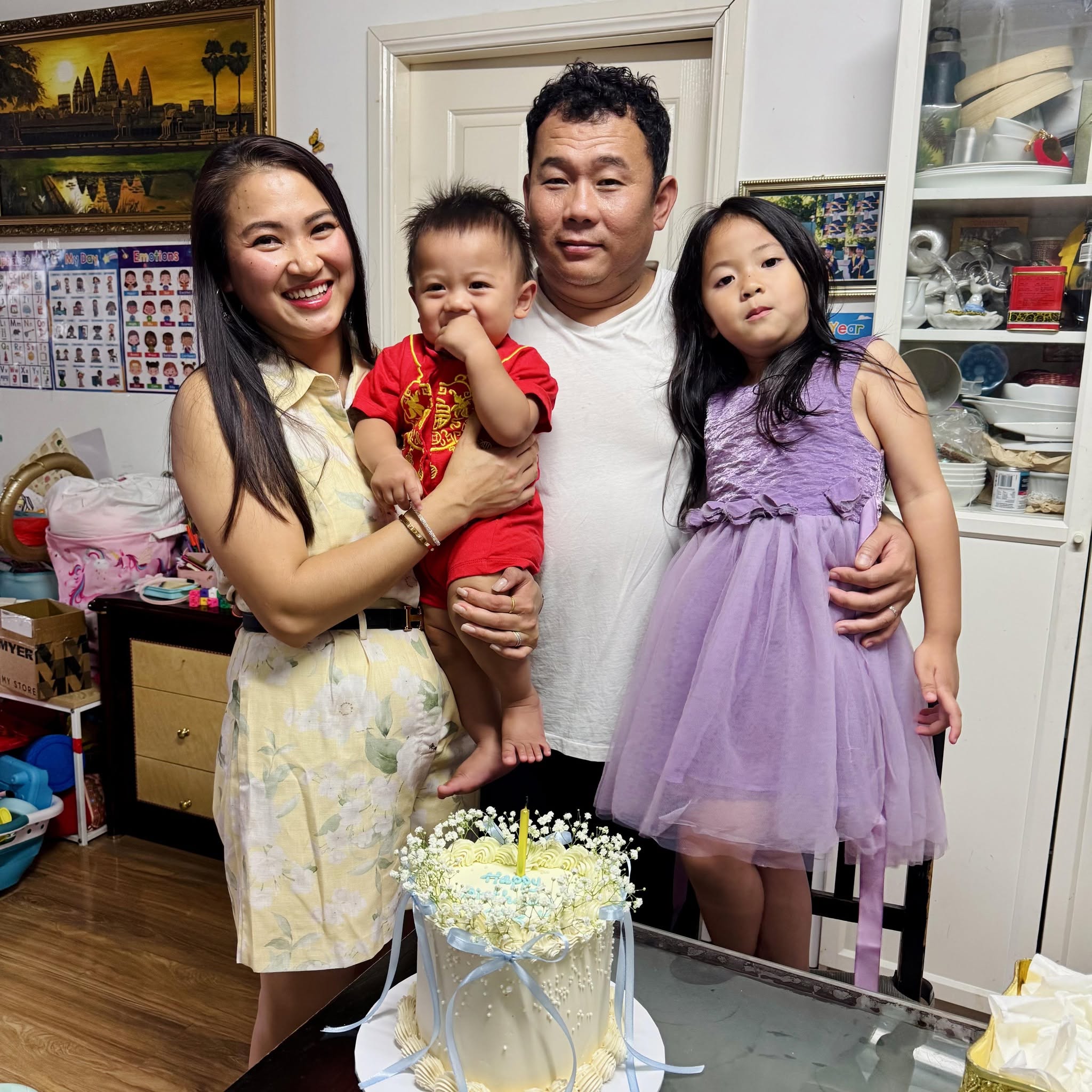 A family of four, a mother to the left smiling with her baby boy, the father in the middle holding his daughter.