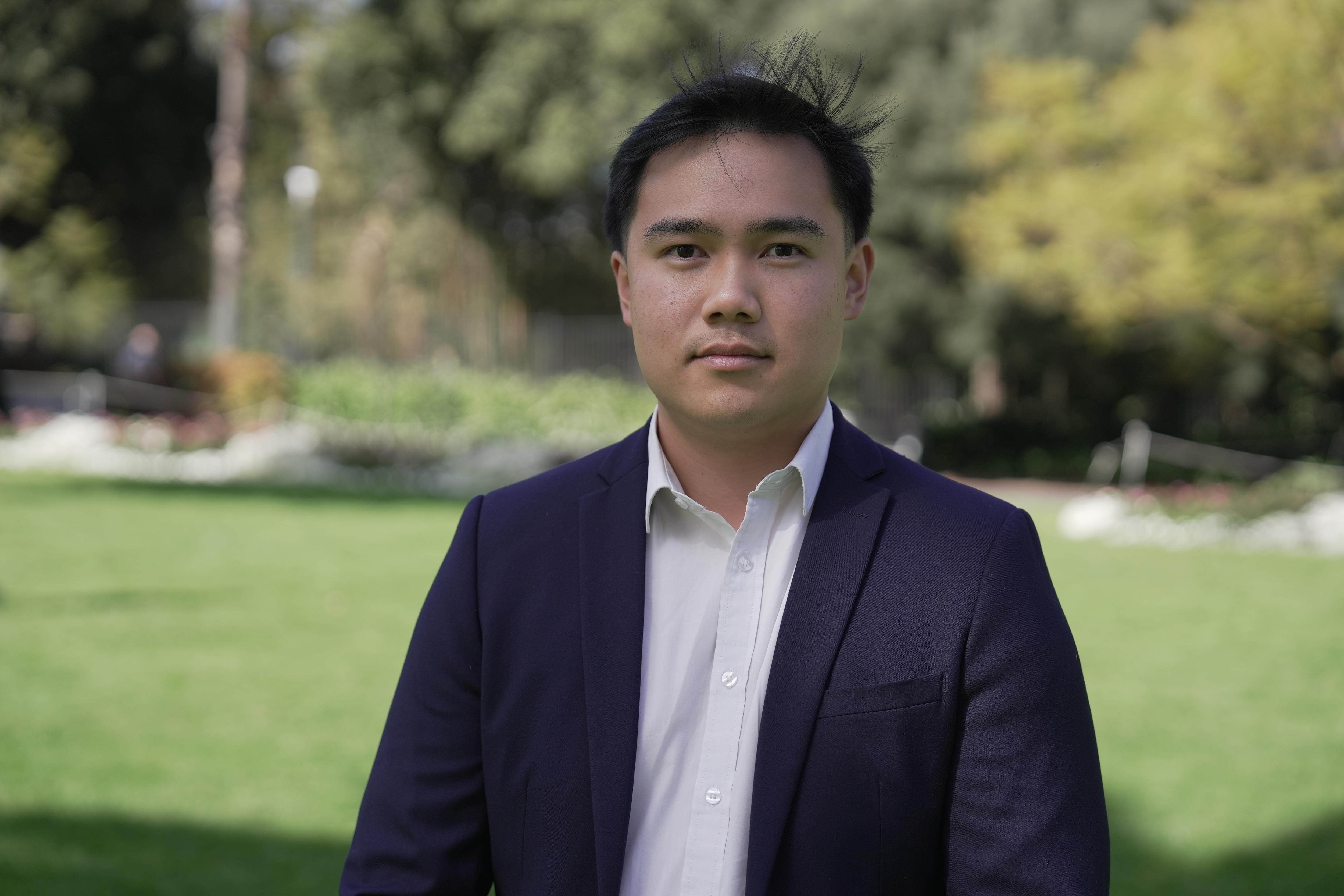a young asian man wearing a white shirt and a blazer in a park