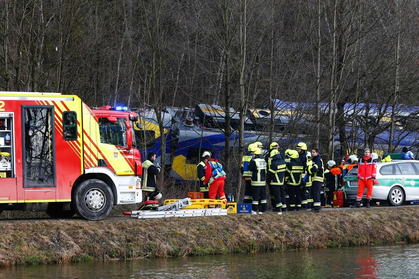 Emergency services stand next to the crashed train.