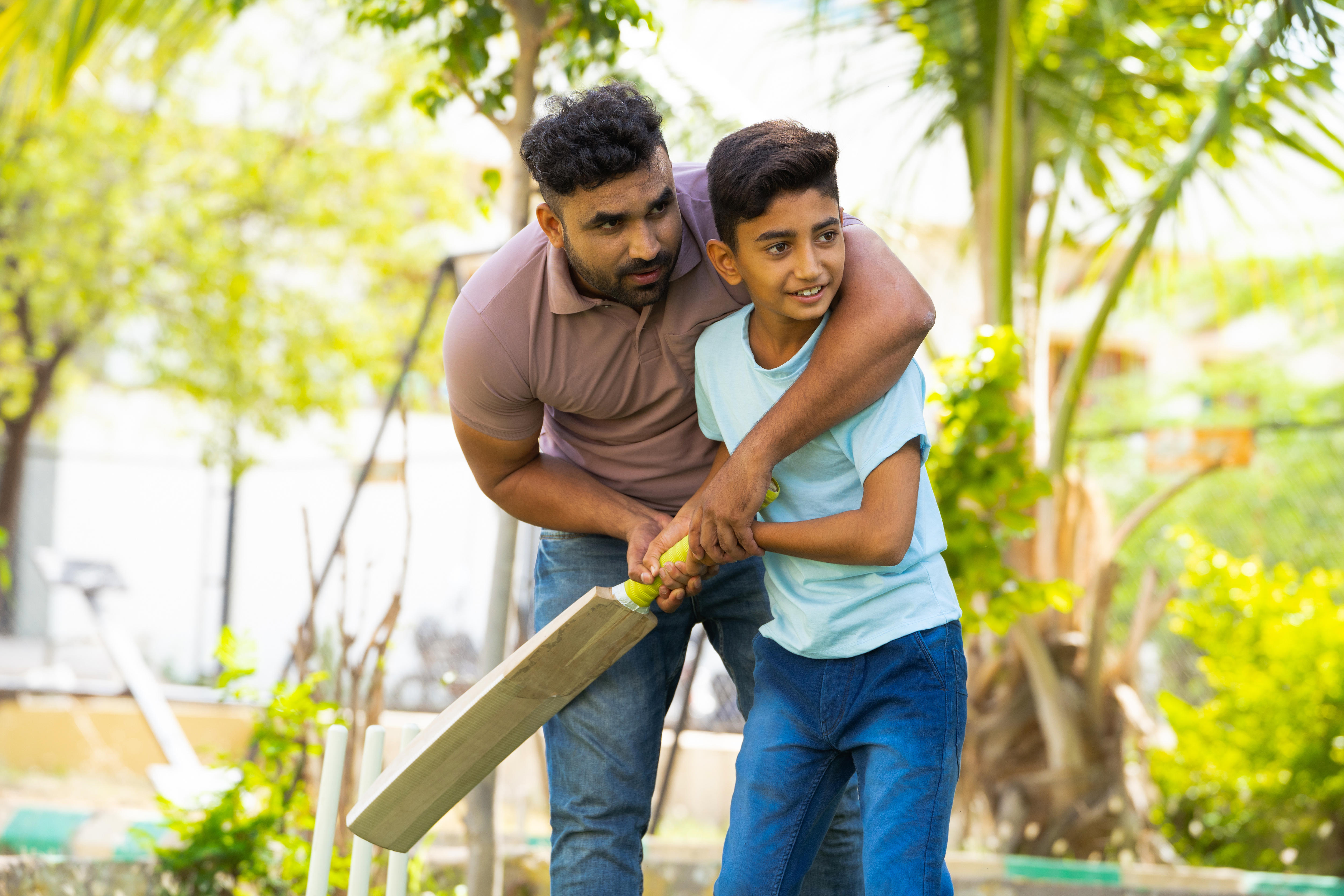father and son playing cricket in the yard