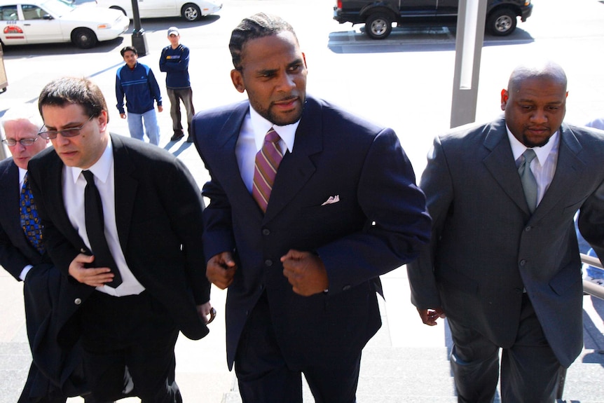 R&B singer R. Kelly, flanked by two men, walks into the Cook County Criminal courthouse.