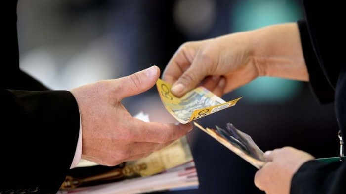 Woman hands over Australian money to a man.