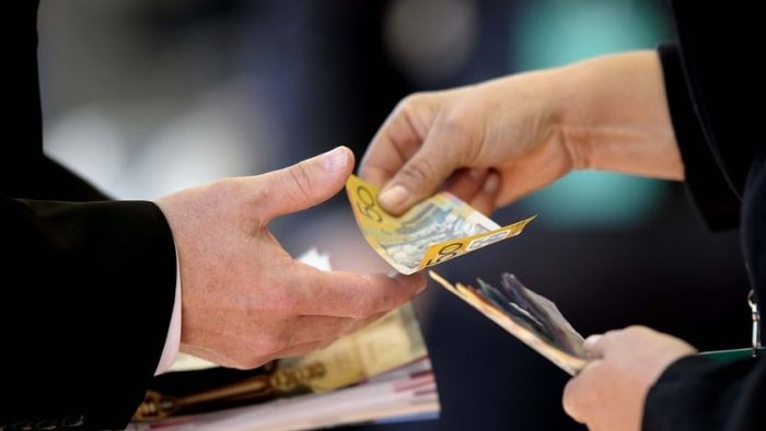 Woman hands over cash to man.