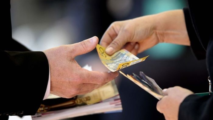 Woman hands over Australian money to a man.