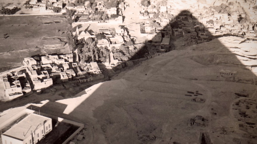 Sepia coloured photo of the shadow of an Egyptian pyramid falling over the settlement below it.