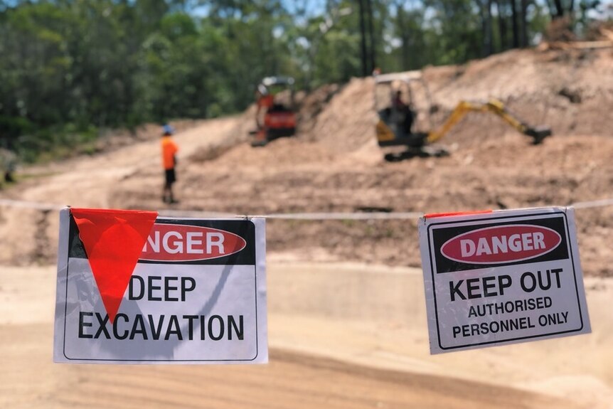 worksite and trucks with signs saying "deep excavation"