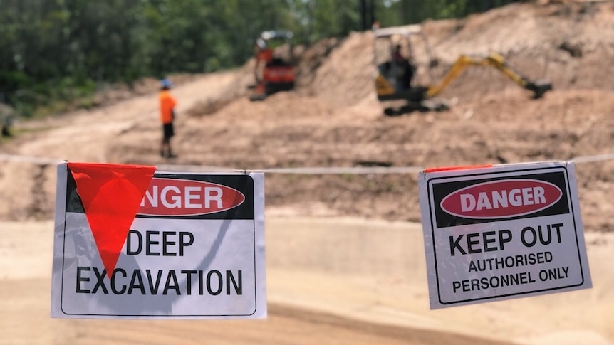 worksite and trucks with signs saying "deep excavation"