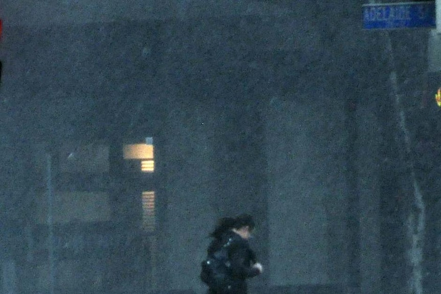 A woman runs through the pouring rain on Adelaide Street in the Brisbane CBD during a freak storm that descended on Brisbane this afternoon.
