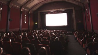 People looking at a blank screen in a cinema.