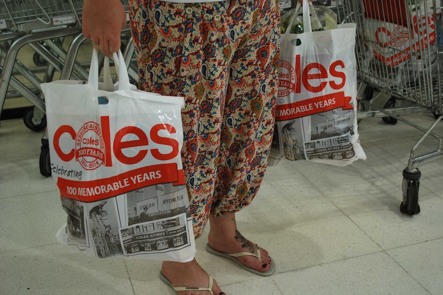 Woman holding reusable plastic shopping bags.