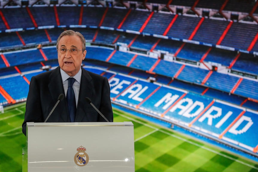 Florentino Perez stands at a lectern in front of Real Madrid's empty Santiago Bernabeu Stadium
