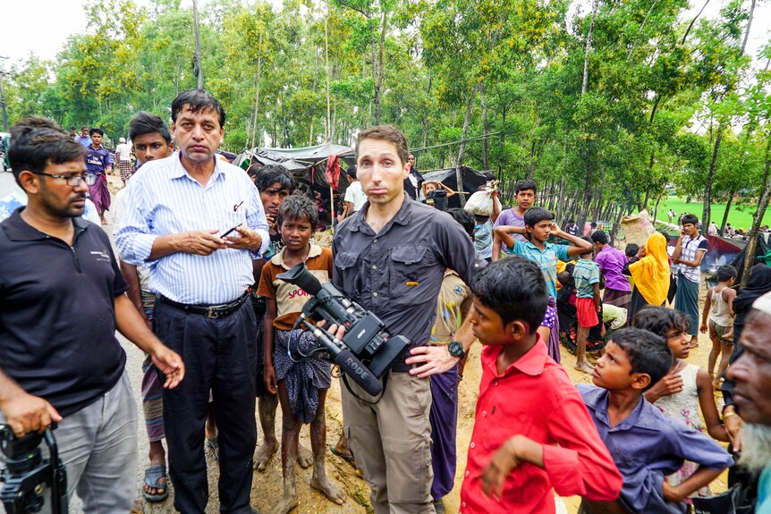James Bennett among a crowd of Rohingya refugees in Bangladesh holding a camera