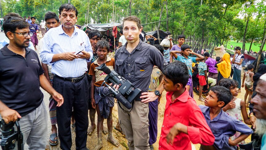James Bennett among a crowd of Rohingya refugees in Bangladesh holding a camera