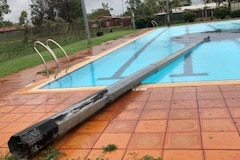 A light pole lying partially submerged in a public swimming pool.