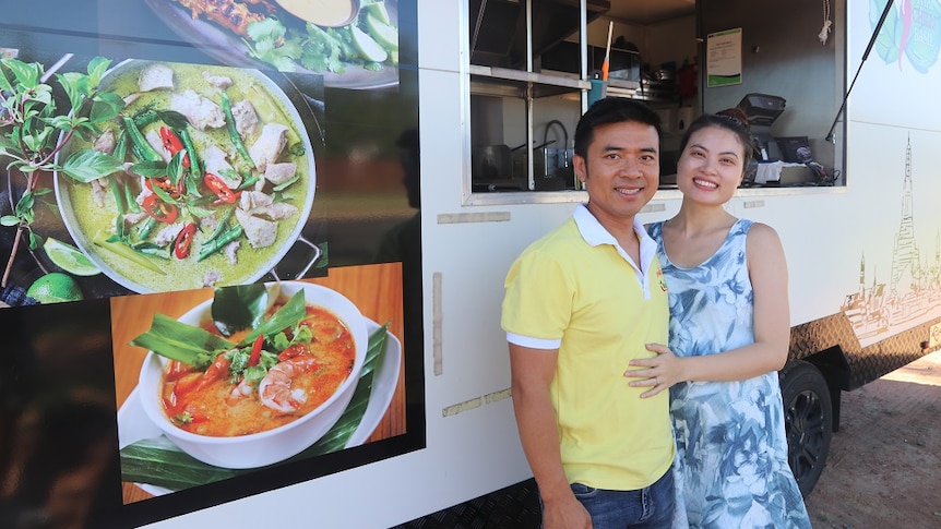 A man and a woman standing in front of a food van