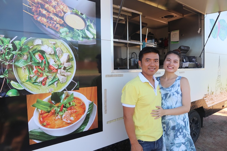 A man and a woman standing in front of a food van