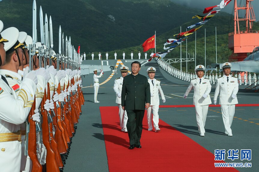 Xi Jinping walks a red carpet as he reviews members of the military, aboard aircraft carrier the Shandong.