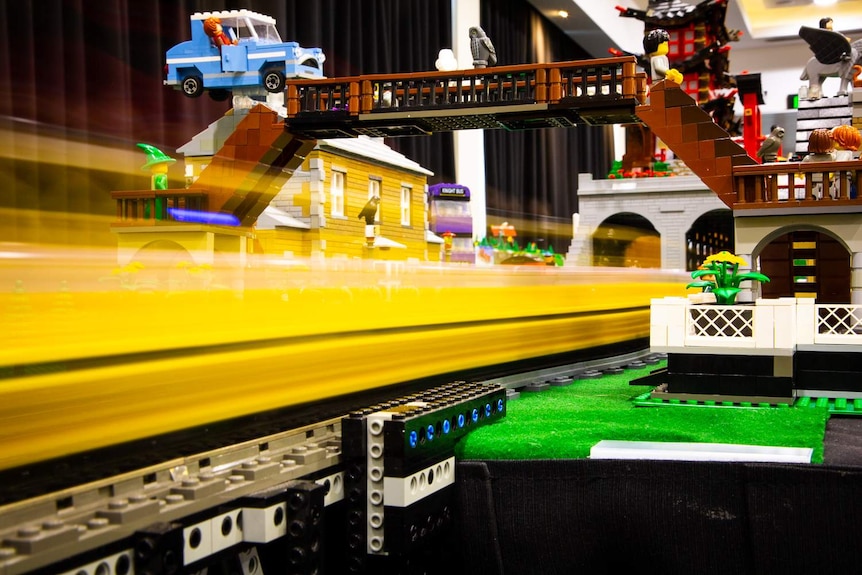 A LEGO train is passing under a Harry Potter LEGO station.