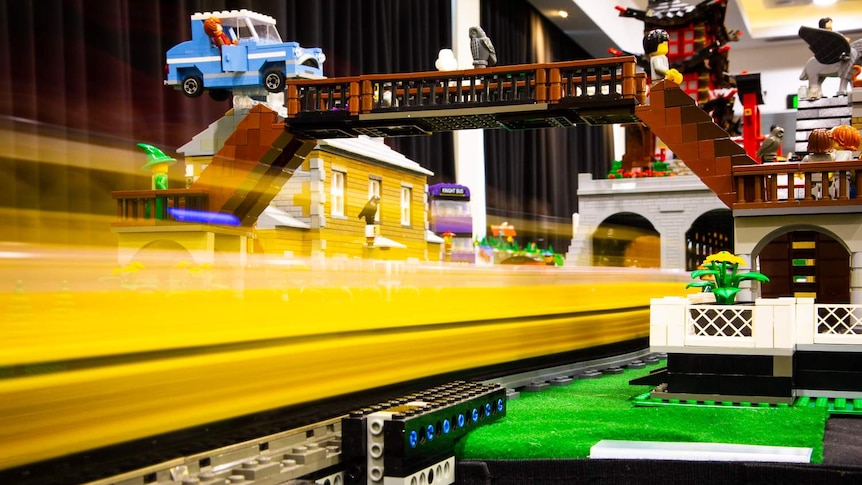 A LEGO train is passing under a Harry Potter LEGO station.