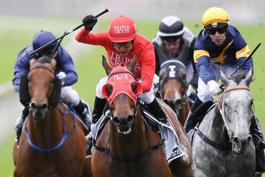 Kerrin McEvoy raises his right arm with the whip in hand across the finish line in The Everest.