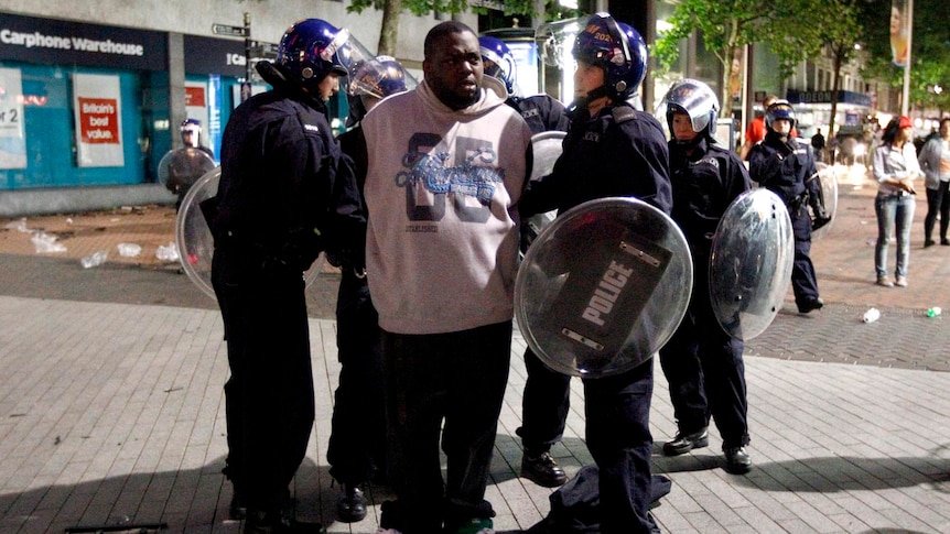 Riot police detain a man in Birmingham