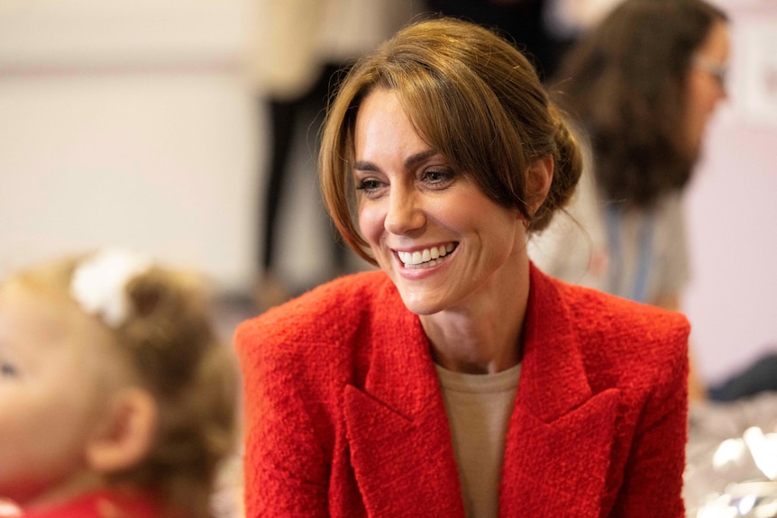 Princess Kate smiles to the side in a red blazer 