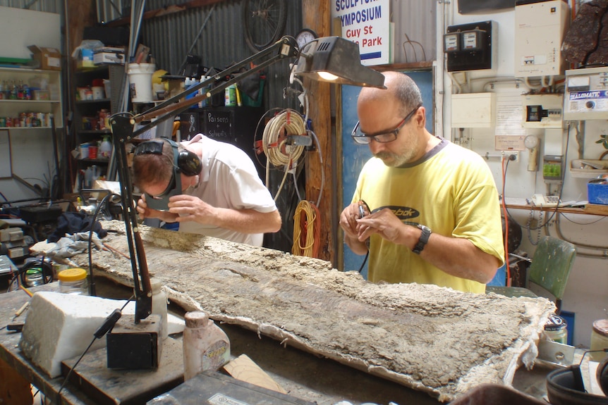 two men working on fossil