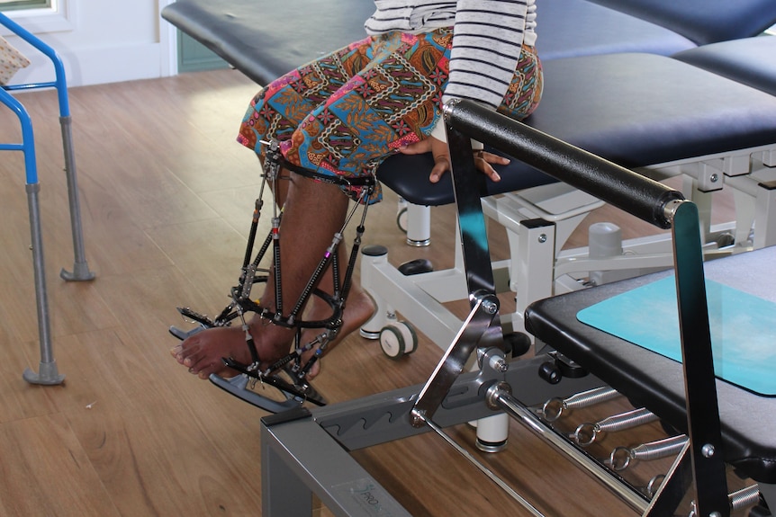 Sonia Paua sits on a bed in a clinic. 