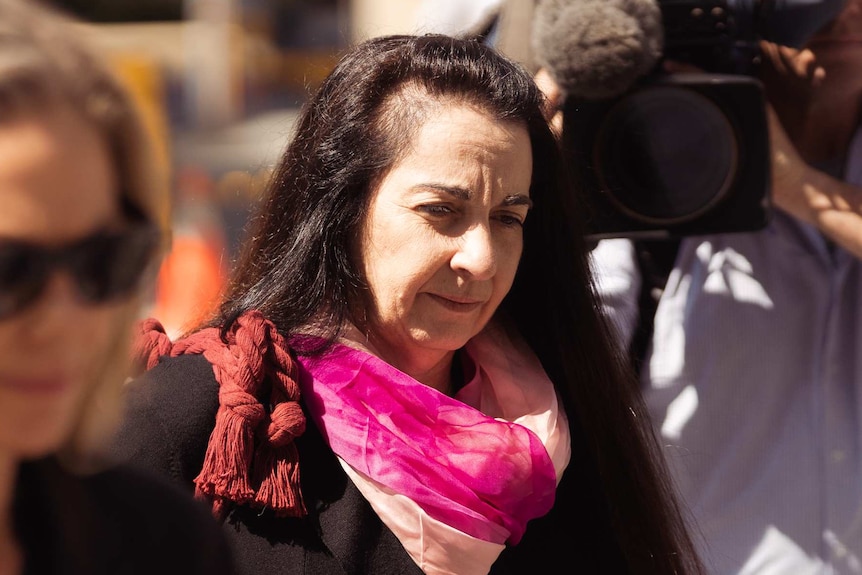 A lawyers dressed in black with a pink scarf outside court.