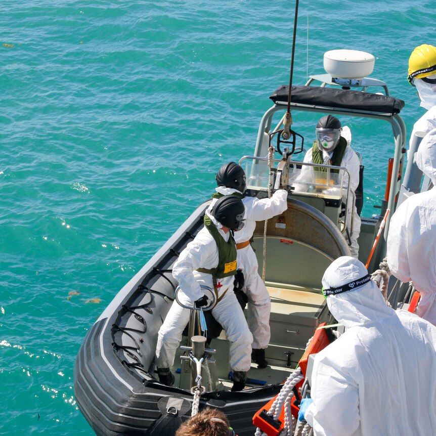 soldiers wearing protective equipment board a small boat during a search and rescue operation