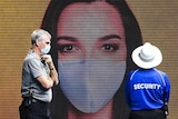 An image of a woman wearing a mask in a mural with two men next to it wearing masks.
