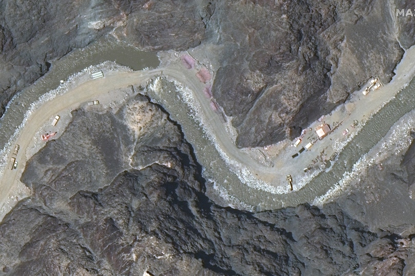 Satellite image of the Galwan Valley that shows trucks on a dirt road by a river as well as structures.
