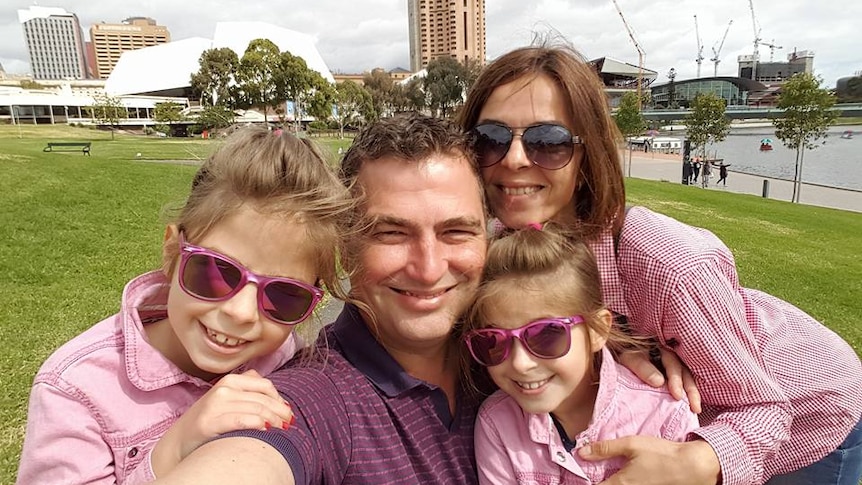 Flaviu Lazar takes a selfie of himself with his partner and two daughters on the banks of Adelaide's Torrens River.