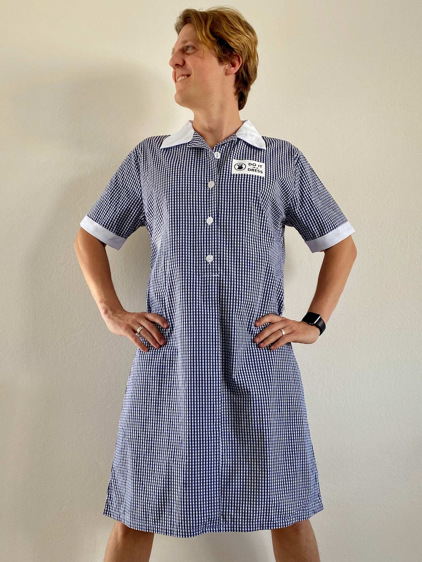 A man wearing a checked dress and standing in a power pose.