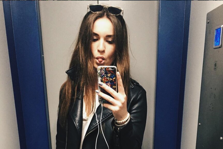 Maria takes a selfie in a lift mirror.