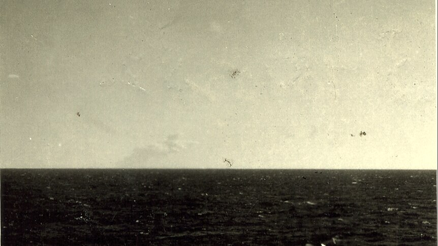 In an old photograph, a plume of smoke is only just visible on the ocean horizon