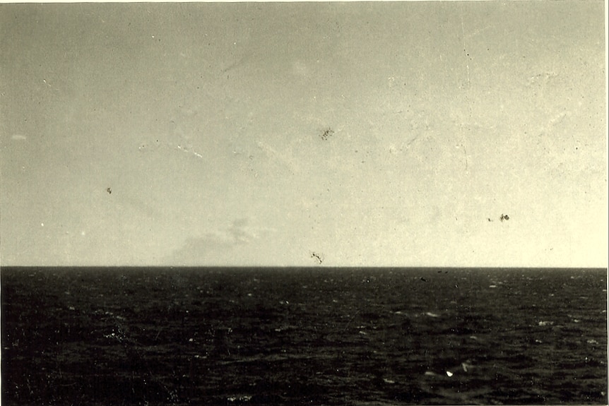 In an old photograph, a plume of smoke is only just visible on the ocean horizon