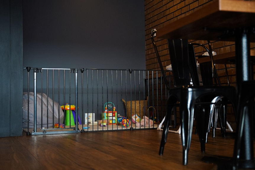 A baby-safe gate at the back of a cafe space leads to a small play area with toys and a beanbag.