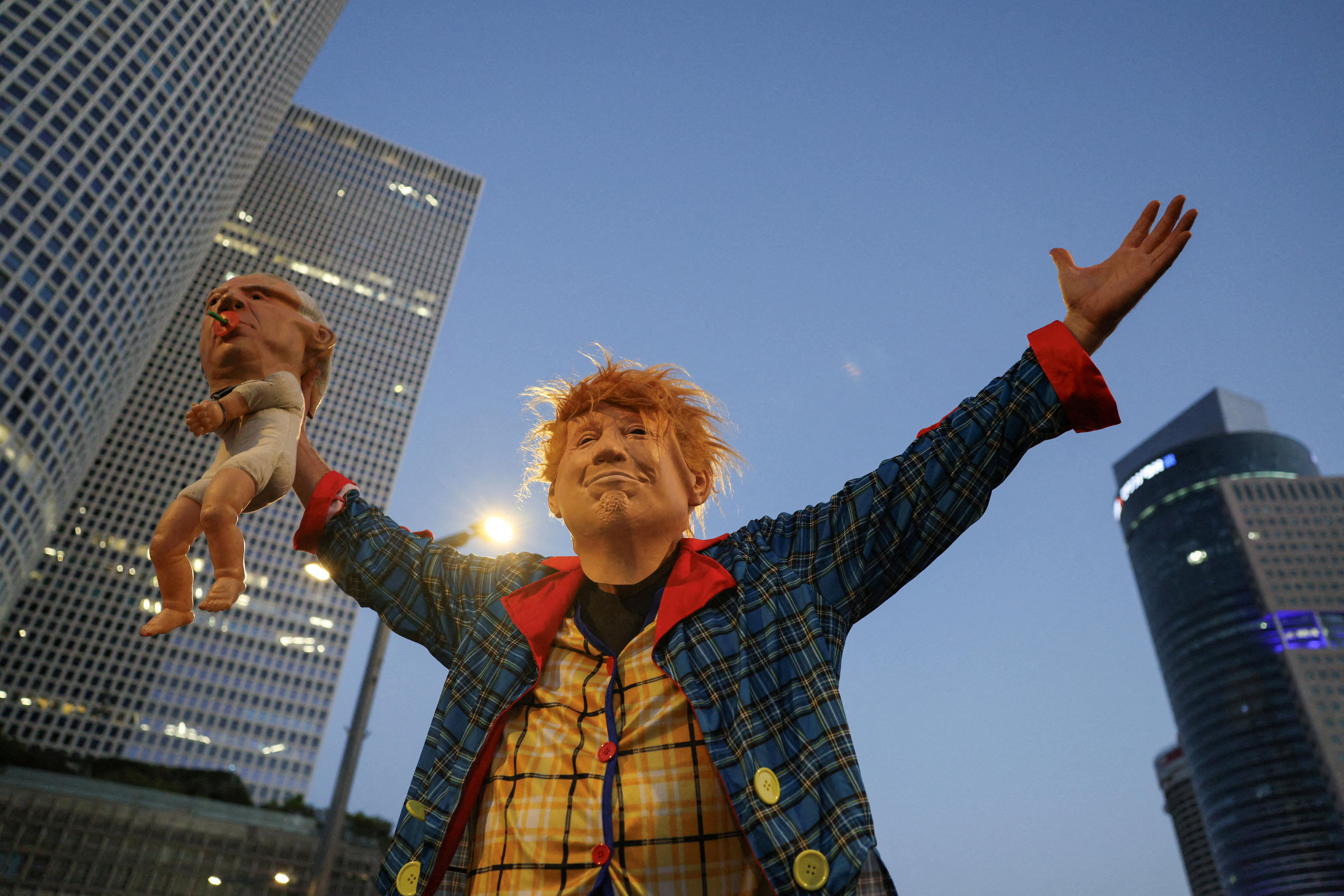 A protester dressed as Donald Trump holding a baby doll with the face of Benjamin Netanyahu