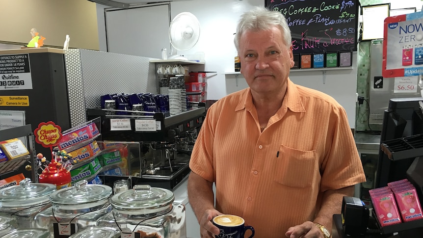 Hervey Bay cafe owner Leonard Norton holds a flat white coffee in his cafe as he poses for a photo