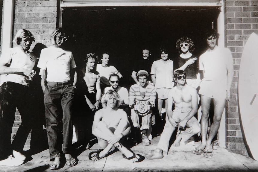 A group of young men who are surfers posed outside the Skipp surfboard making factory