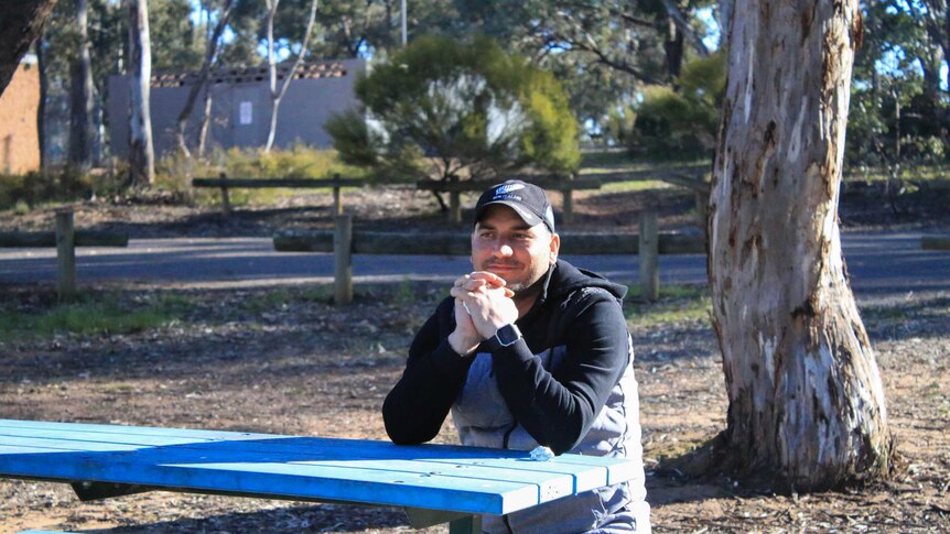 Samar sits at a table in a park in Melbourne