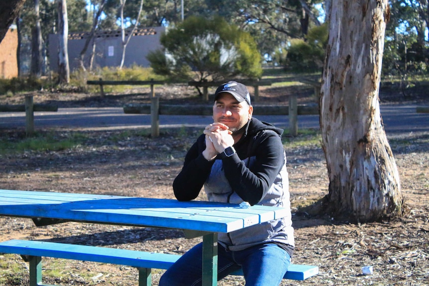 Samar sits at a table in a park in Melbourne