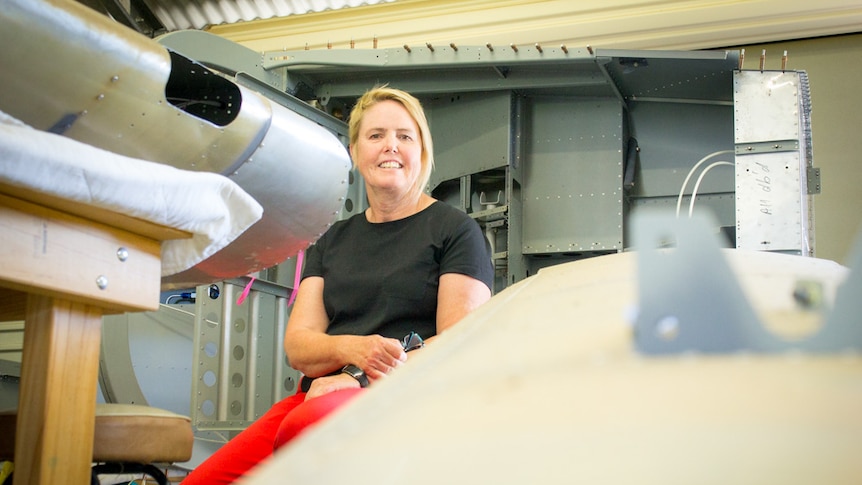 Retired educator Wendy Featherston sits among pieces of a plane she is building in her backyard shed