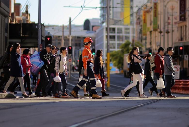 Pedestrians cross a road near a construction site in central Sydney