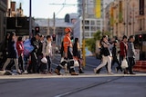 Pedestrians cross a road near a construction site in central Sydney