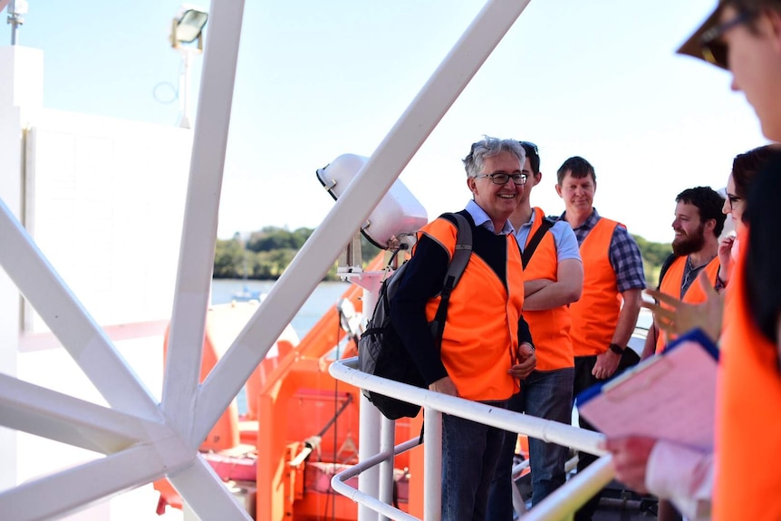 A man smiles as he gives a tour to students on board the Investigator.