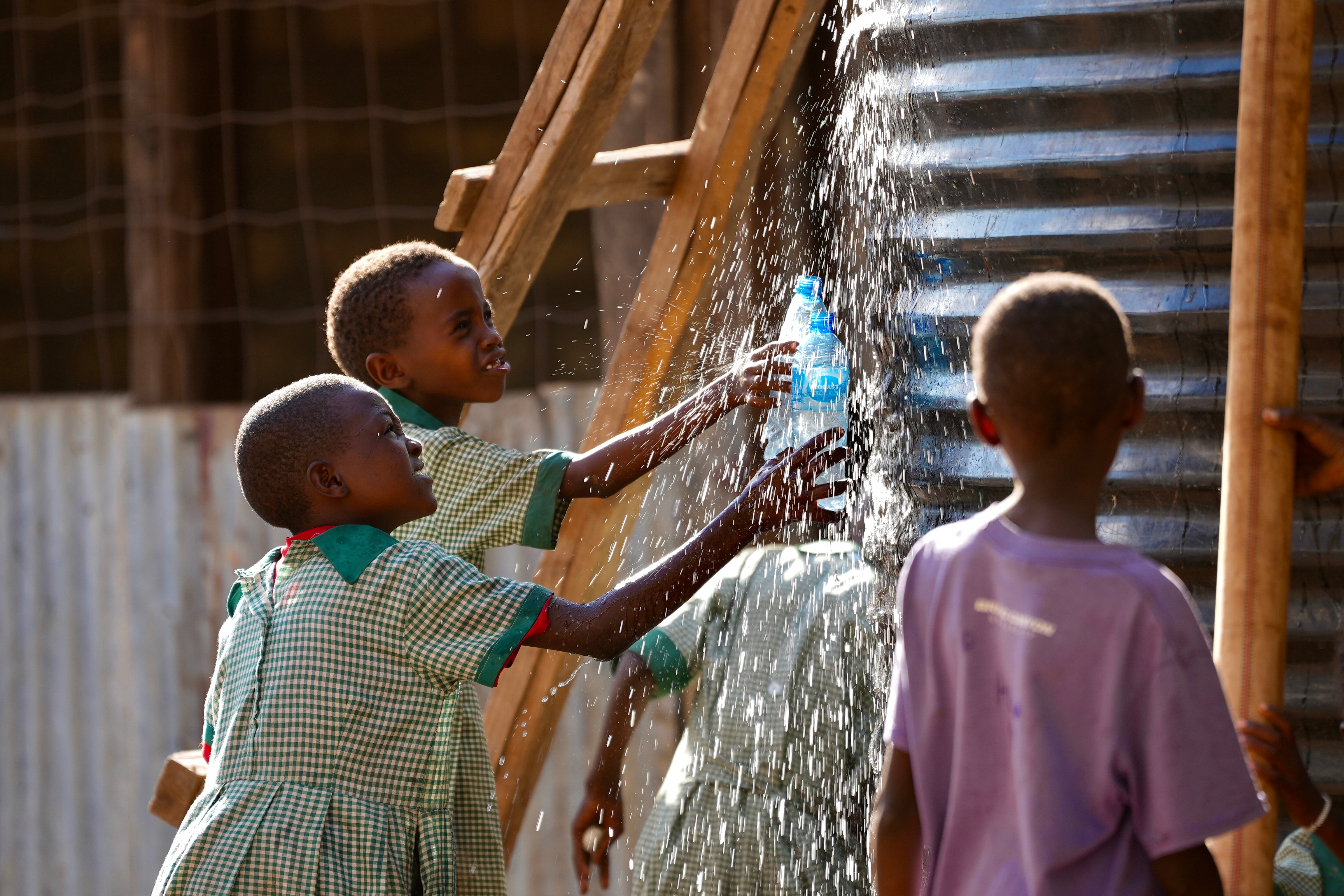 A group of kids catching water near a water tank